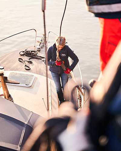 Fotografie einer Frau auf einem Segelboot, die ein Tau befestigt.